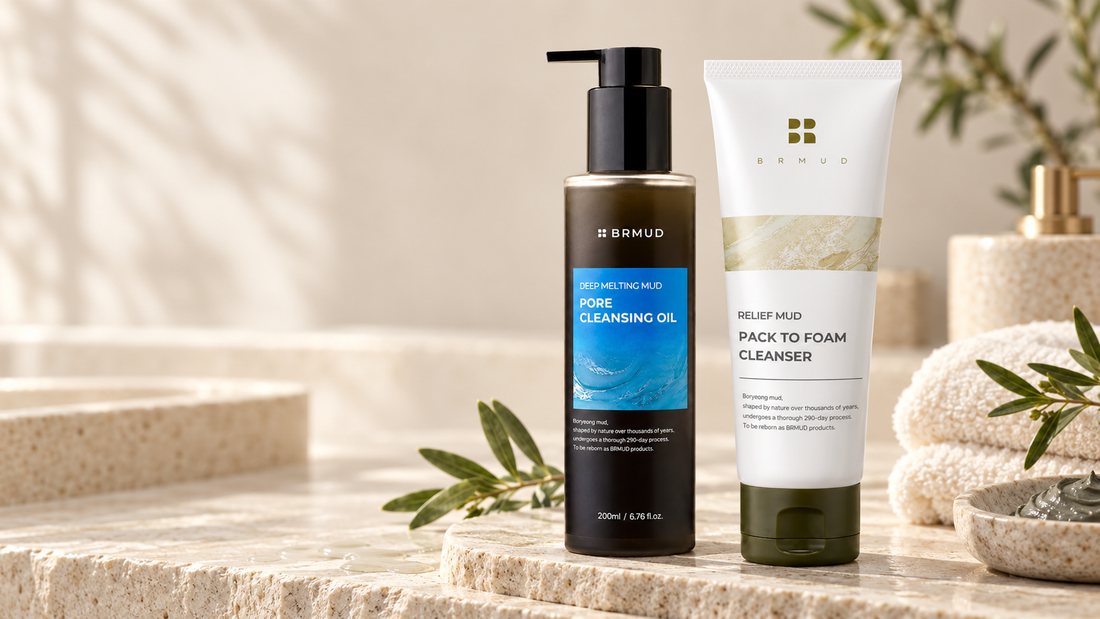 BRMUD Deep Melting Mud Pore Cleansing Oil and BRMUD Relief Mud Pack to Foam Cleanser arranged as a two-step cleansing routine on a warm stone vanity