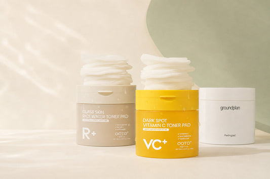 Three Korean toner pad products on a soft cream and pale sage background: Rice Water Toner Pad, Vitamin C Toner Pad, and groundplan Peeling Pad.
