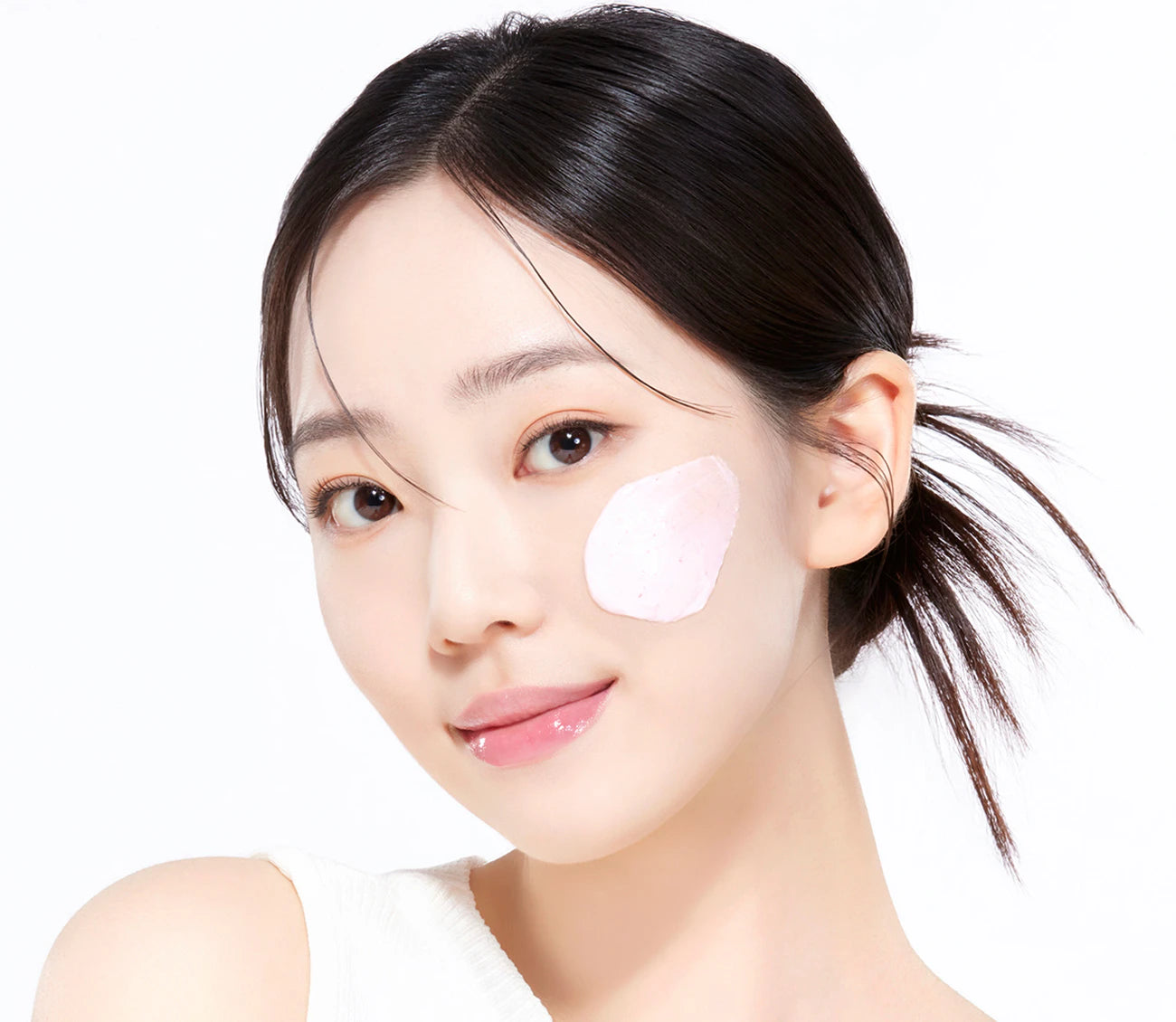 Woman with a skincare product on her face against a white background