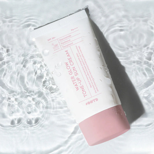#OOTD Water Glow Tone-Up Sun Cream tube lying on rippling water with droplets on the packaging.