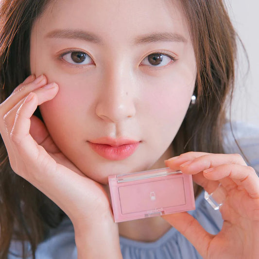 Model holding the rom&nd Better Than Cheek W02 Strawberry Milk compact beside a softly flushed cheek