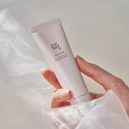 Beauty of Joseon Revive Eye Serum Ginseng + Retinal 30ml pink pump tube held in a hand over soft white fabric.