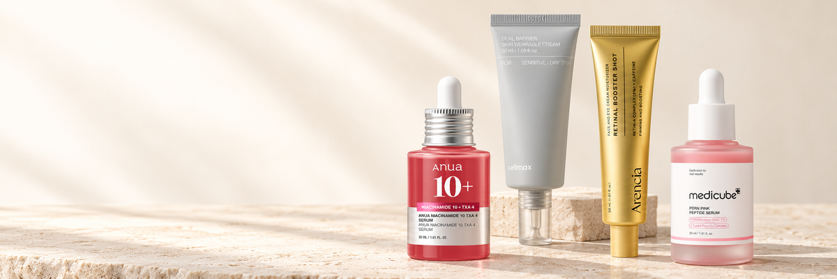 ANUA Niacinamide and TXA serum, celimax barrier cream, Arencia retinal serum, and medicube PDRN serum arranged on warm ivory stone.